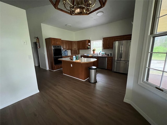 kitchen featuring appliances with stainless steel finishes, a kitchen island, an inviting chandelier, and dark hardwood / wood-style floors