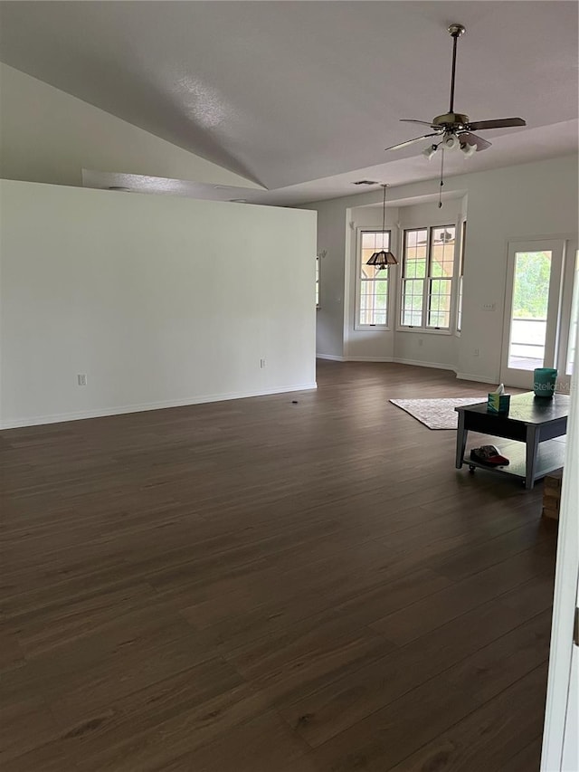 empty room featuring a healthy amount of sunlight, ceiling fan, dark hardwood / wood-style floors, and vaulted ceiling