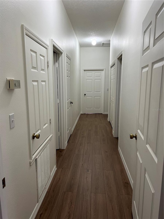 corridor featuring a textured ceiling and dark hardwood / wood-style floors