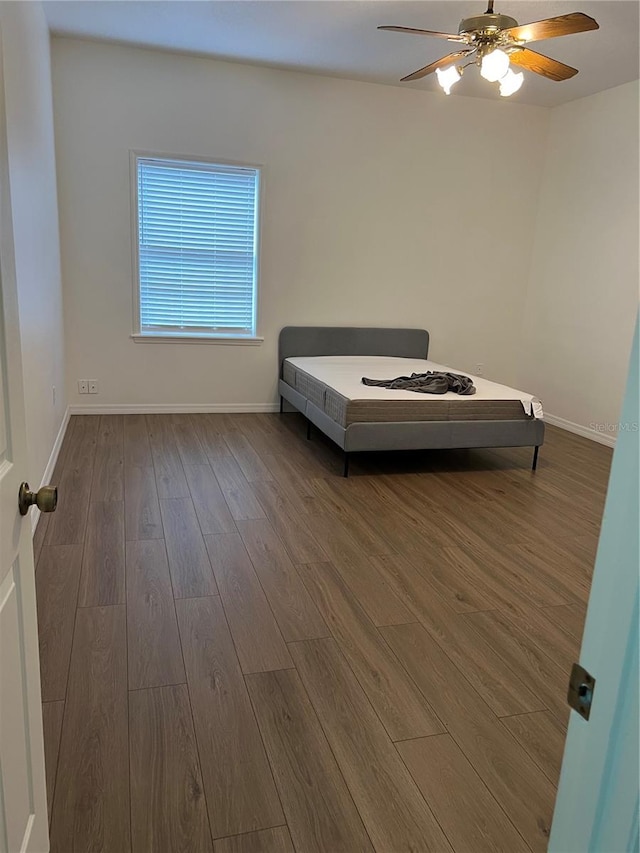 unfurnished bedroom with ceiling fan and dark hardwood / wood-style floors