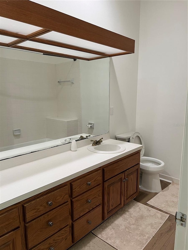 bathroom featuring vanity, toilet, hardwood / wood-style flooring, and a tile shower