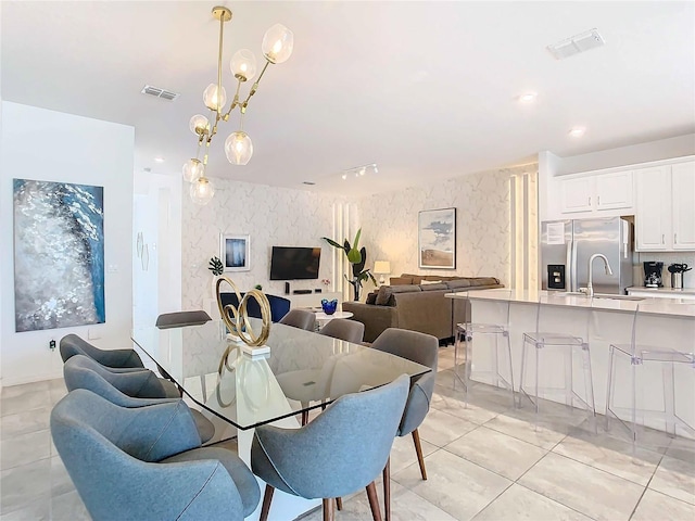 dining space featuring light tile patterned floors, a notable chandelier, and sink