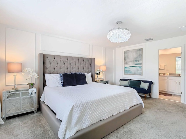 bedroom featuring light carpet, ensuite bathroom, and a chandelier