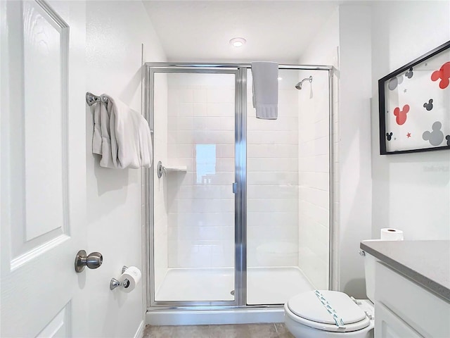 bathroom featuring toilet, a shower with door, and vanity