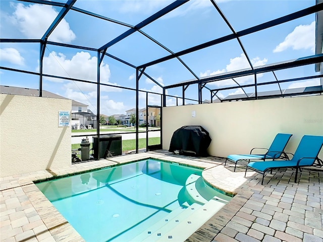 view of swimming pool featuring glass enclosure and a patio