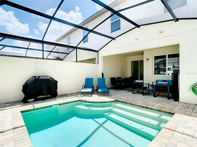 view of pool with glass enclosure, a hot tub, and a patio