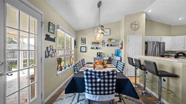 dining space featuring light tile patterned floors and vaulted ceiling