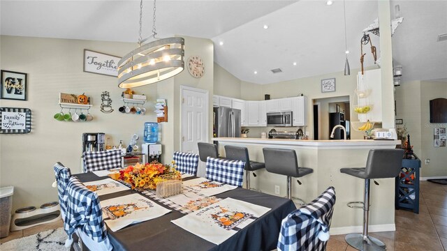 dining area featuring high vaulted ceiling, an inviting chandelier, and tile patterned floors