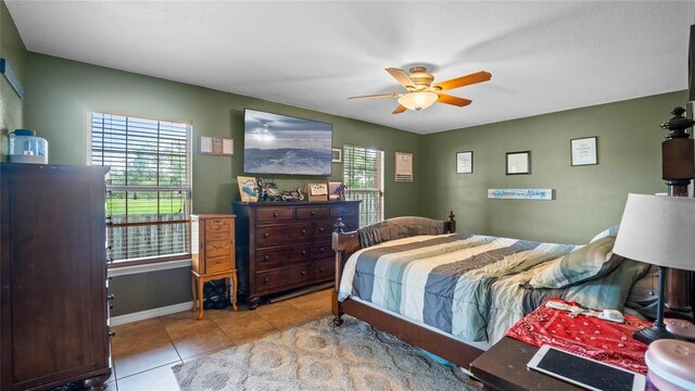 bedroom with multiple windows, ceiling fan, and light tile patterned floors