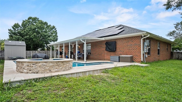 rear view of property featuring a patio area, solar panels, a storage unit, and a pool with hot tub