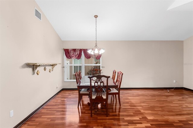 dining space with a notable chandelier, lofted ceiling, and hardwood / wood-style floors