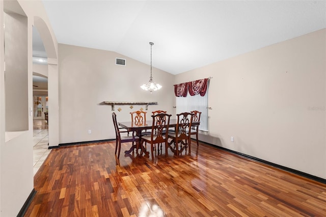 dining room with hardwood / wood-style flooring, lofted ceiling, and a notable chandelier