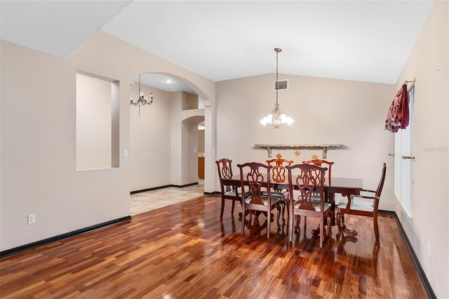 dining space with a notable chandelier, lofted ceiling, and hardwood / wood-style floors