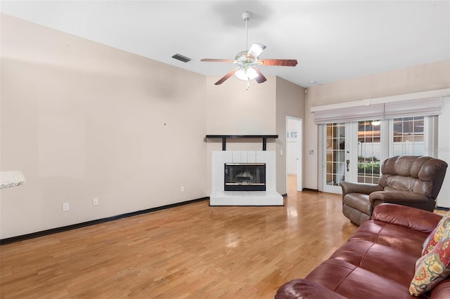 unfurnished living room featuring light wood-type flooring, vaulted ceiling, a tiled fireplace, and ceiling fan