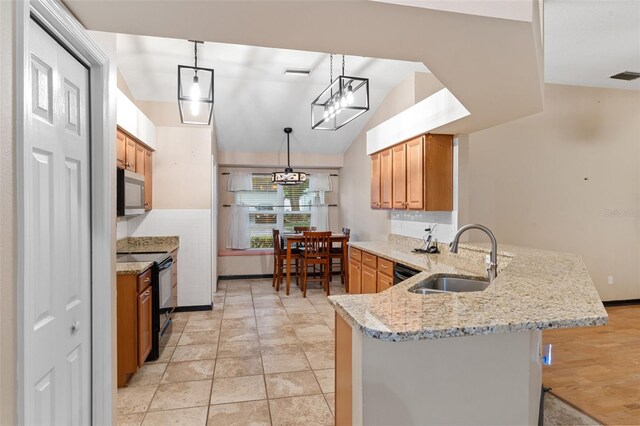 kitchen with hanging light fixtures, sink, kitchen peninsula, black appliances, and a kitchen bar