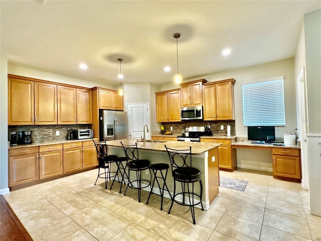 kitchen with appliances with stainless steel finishes, an island with sink, hanging light fixtures, a breakfast bar, and light tile patterned flooring