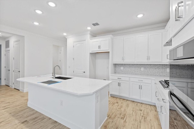 kitchen featuring a kitchen island with sink, sink, and white cabinets