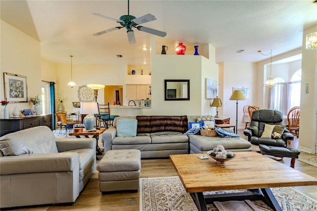 living room with high vaulted ceiling, ceiling fan with notable chandelier, and light hardwood / wood-style floors