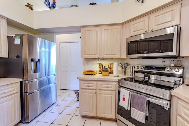 kitchen with stainless steel appliances, light tile patterned floors, light brown cabinetry, and tasteful backsplash