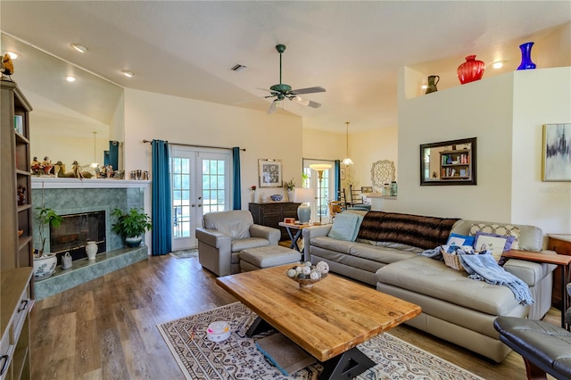 living room featuring dark wood-type flooring, ceiling fan, a premium fireplace, and french doors