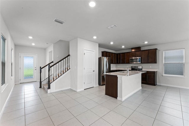 kitchen featuring stainless steel appliances, a center island with sink, light tile patterned floors, and sink