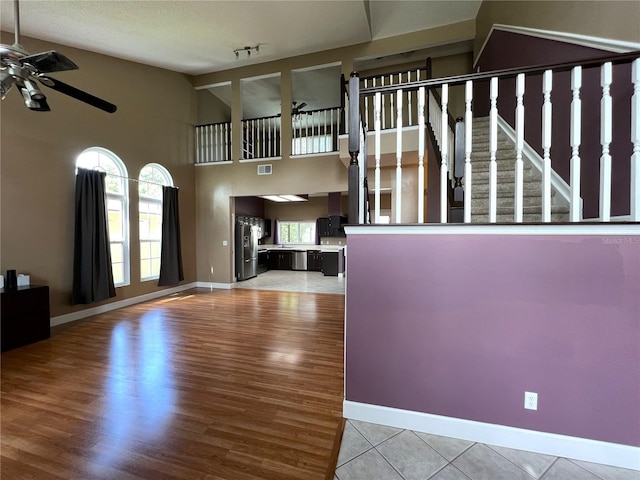 interior space with light wood-type flooring, a textured ceiling, high vaulted ceiling, and ceiling fan