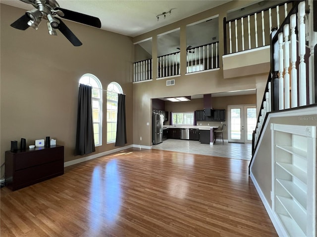 unfurnished living room with high vaulted ceiling, ceiling fan, a wealth of natural light, and hardwood / wood-style flooring