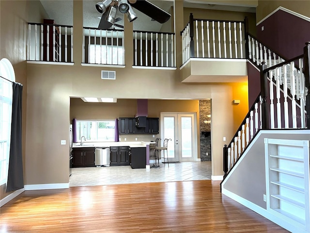 kitchen featuring appliances with stainless steel finishes, light hardwood / wood-style floors, sink, a high ceiling, and ceiling fan