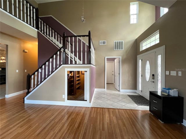 entryway with light hardwood / wood-style floors and a towering ceiling