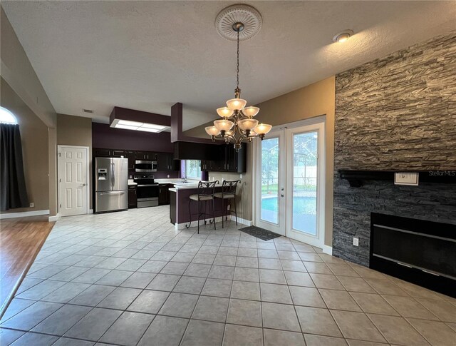 kitchen featuring a textured ceiling, a chandelier, stainless steel appliances, kitchen peninsula, and light hardwood / wood-style floors