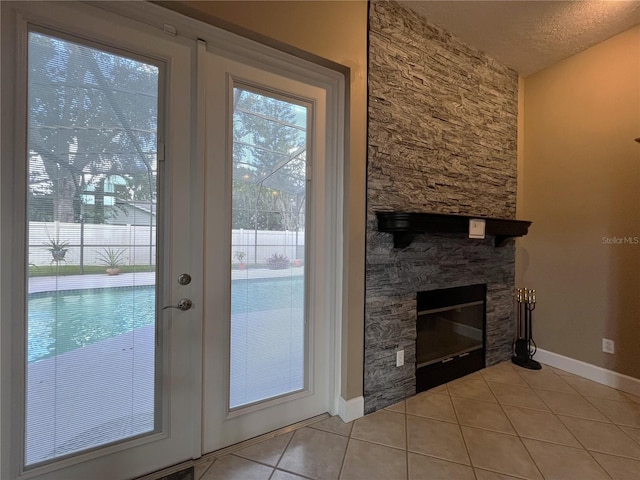 entryway featuring light tile patterned floors, a textured ceiling, and a stone fireplace