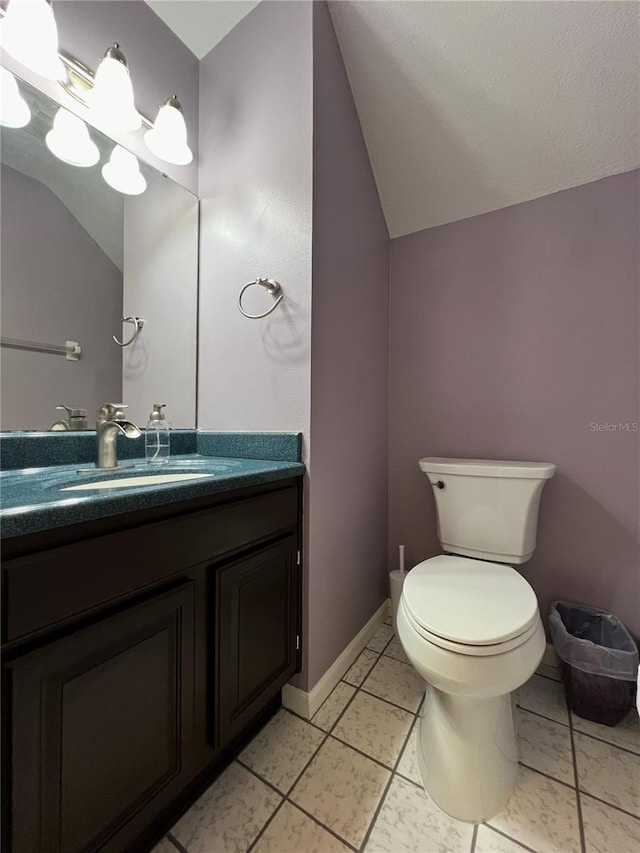 bathroom with vanity, toilet, tile patterned flooring, and lofted ceiling