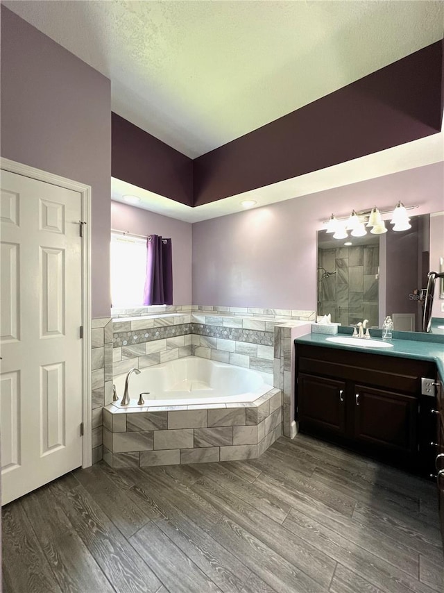 bathroom featuring independent shower and bath, hardwood / wood-style flooring, a textured ceiling, and vanity