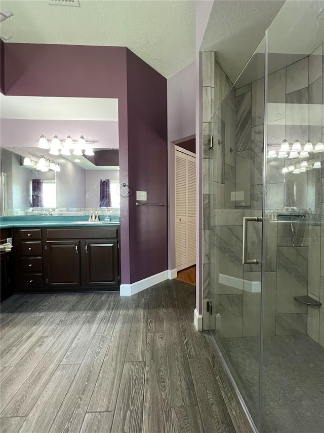 bathroom featuring an enclosed shower, hardwood / wood-style flooring, vaulted ceiling, vanity, and a textured ceiling