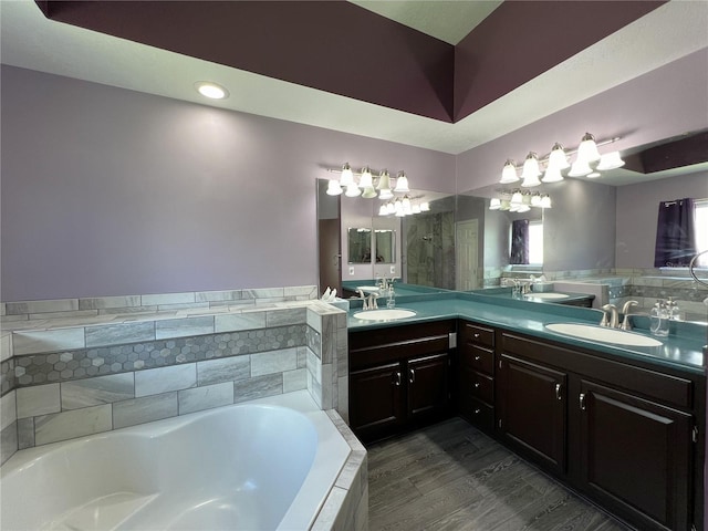 bathroom with hardwood / wood-style floors, tiled tub, and vanity