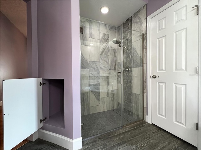 bathroom featuring a tile shower and wood-type flooring