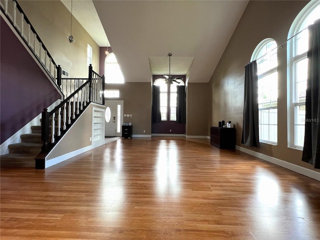 entryway featuring a towering ceiling, a chandelier, and light hardwood / wood-style floors