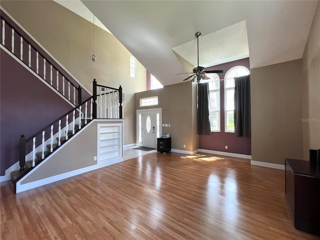 unfurnished living room featuring a textured ceiling, ceiling fan, high vaulted ceiling, and hardwood / wood-style flooring