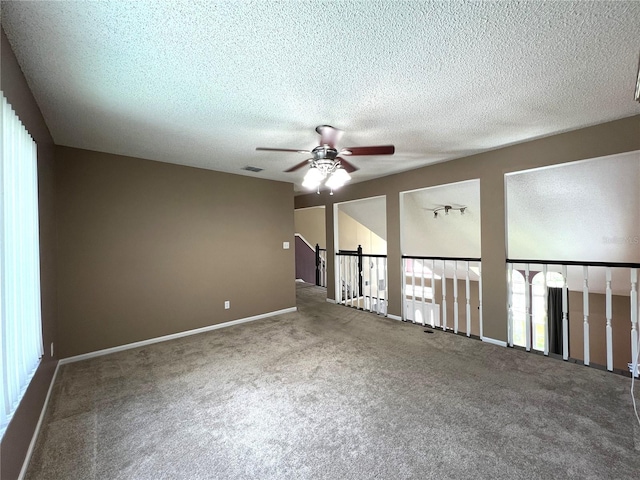 carpeted empty room featuring ceiling fan, plenty of natural light, and a textured ceiling