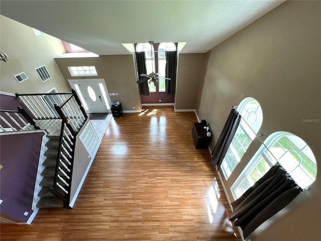 interior space with a high ceiling, wood-type flooring, and ceiling fan