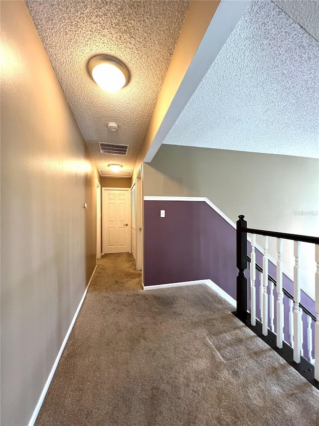 hallway featuring a textured ceiling and carpet