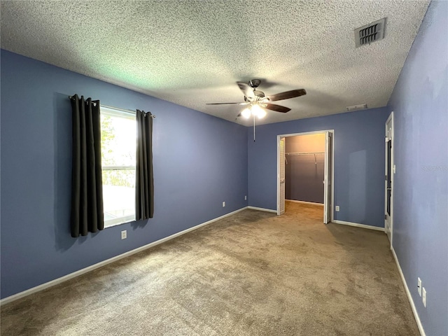 carpeted spare room featuring a textured ceiling and ceiling fan