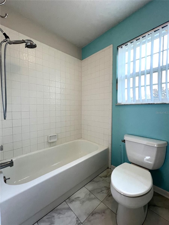 bathroom featuring tiled shower / bath, toilet, and a textured ceiling