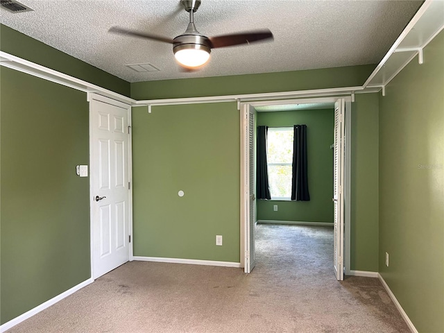 carpeted spare room featuring ceiling fan and a textured ceiling