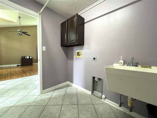 laundry area with hookup for a washing machine, light hardwood / wood-style flooring, ceiling fan, cabinets, and a textured ceiling