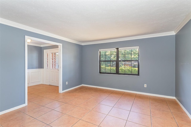 tiled empty room featuring ornamental molding and a textured ceiling