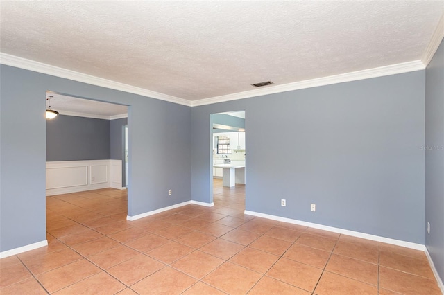 tiled spare room with a textured ceiling and ornamental molding