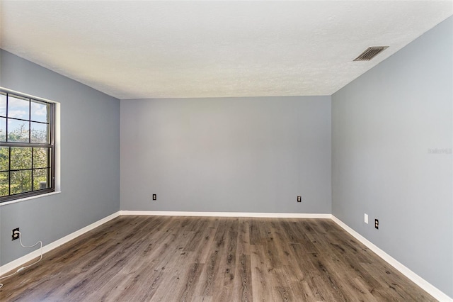 empty room with a textured ceiling and dark wood-type flooring