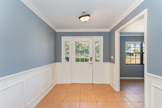 foyer with light tile patterned floors, wainscoting, and crown molding