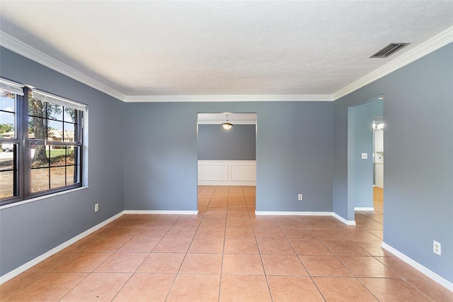 empty room featuring visible vents, ornamental molding, a textured ceiling, light tile patterned flooring, and baseboards